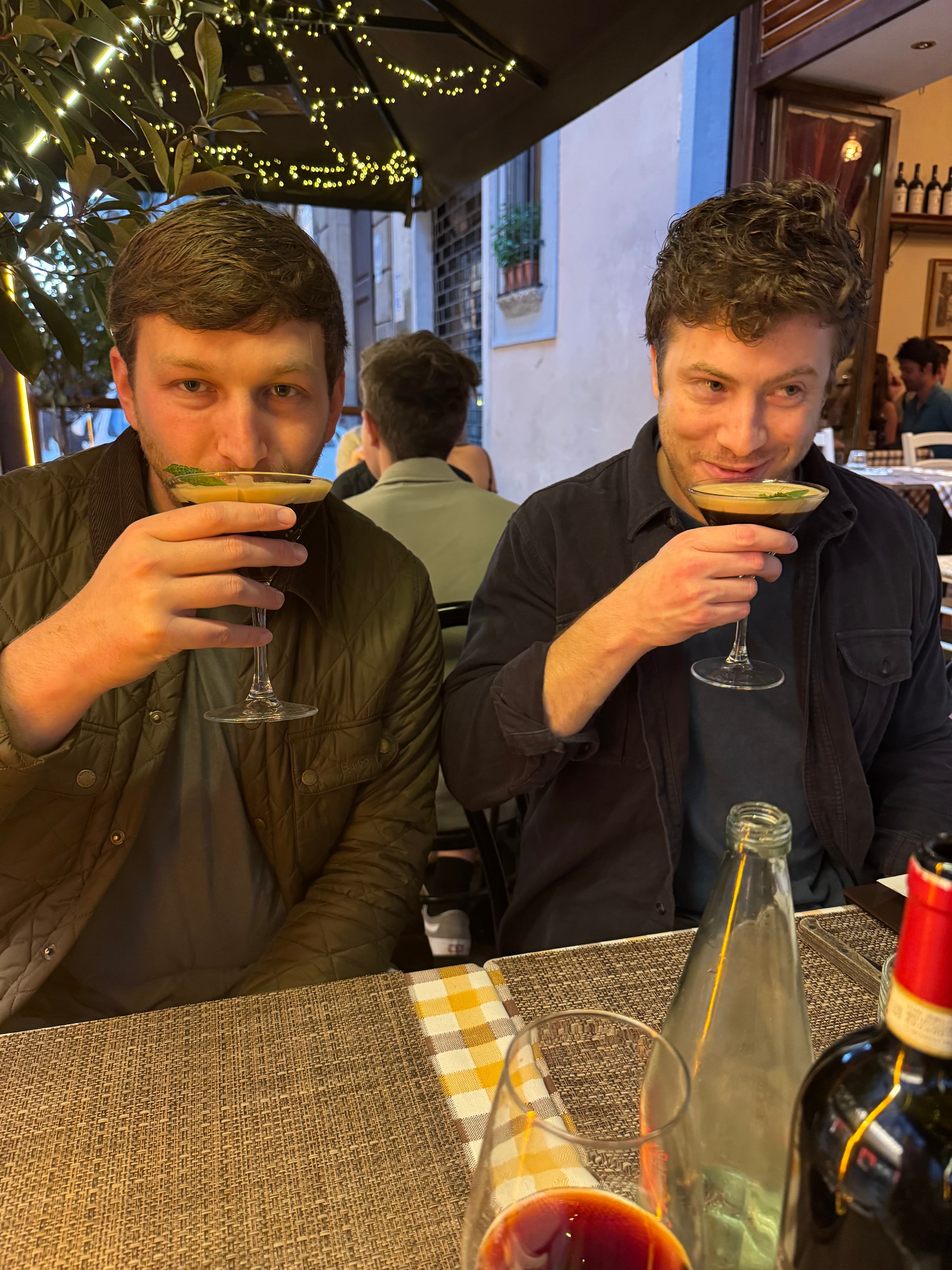 Two guys holding up cocktails